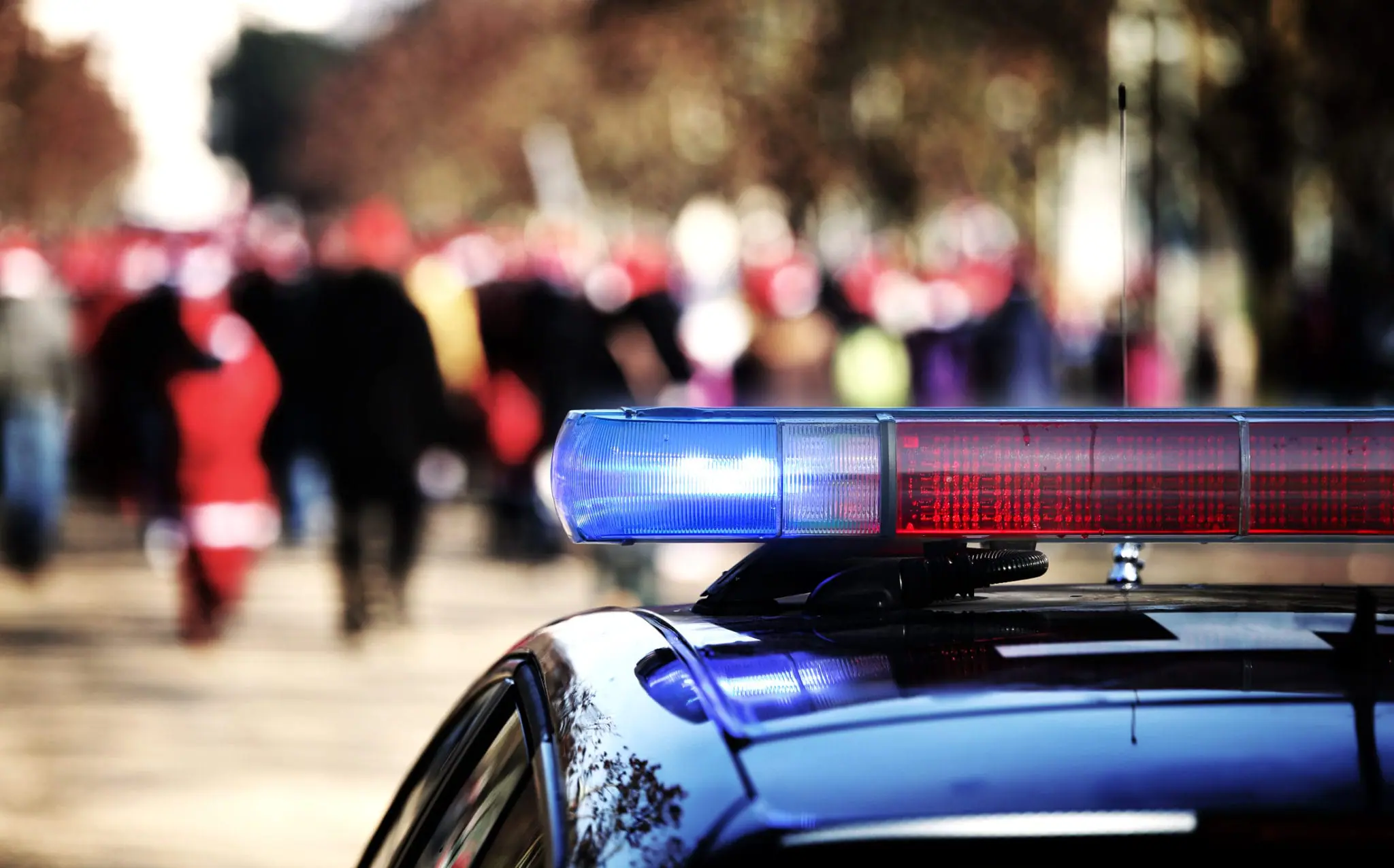 Crowd of people and the siren on top of a police car | COVID-19