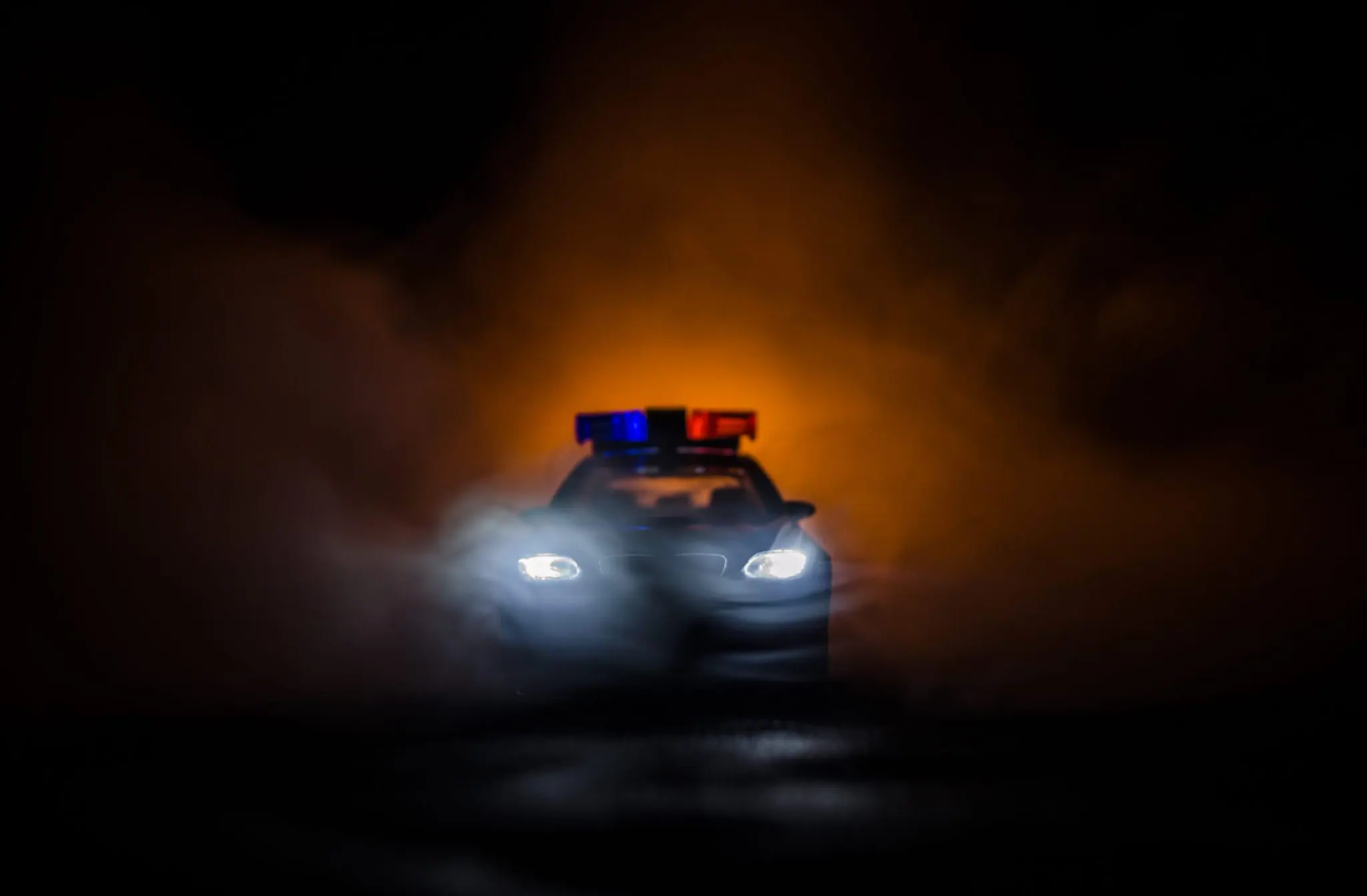 Police vehicle with headlights on in the dark | False Statement