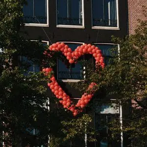 Red balloons in a heart shape on a building | Premium Pay Update