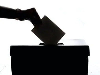 Hand placing a ballot envelope in a box | Michigan Election Volunteers