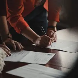 A woman signing a sheet of paper with a pen | Michigan Funding Bill for Secondary Roads