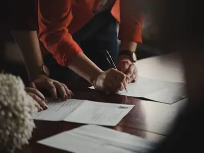A woman signing a sheet of paper with a pen | Michigan Funding Bill for Secondary Roads