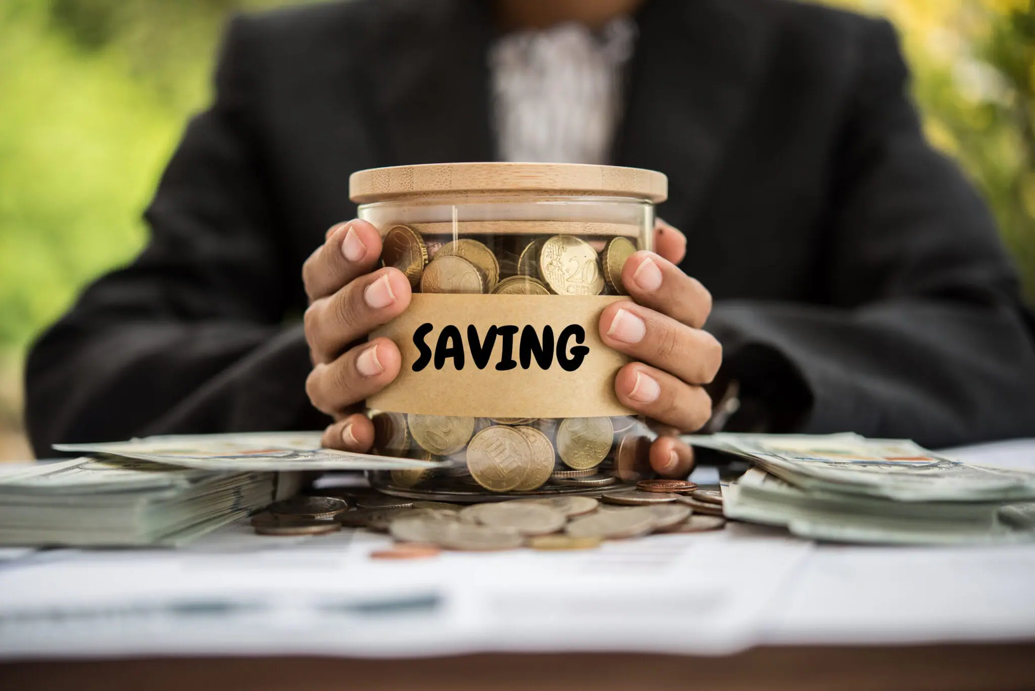 Man holding jar of money for emergency funds. | Financial Goals