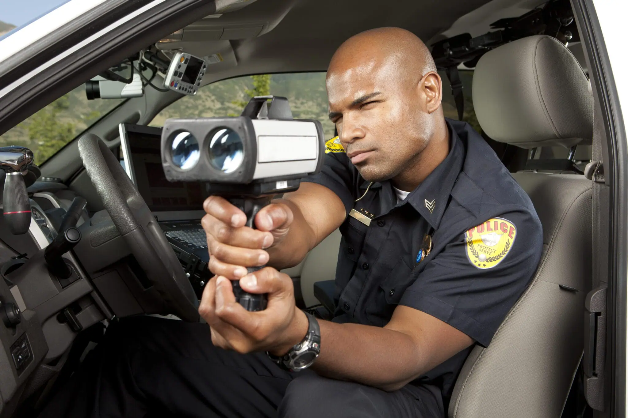 Lapeer County Road Patrol Deputy | An officer sitting in his patrol car with the door open and holding a laser speed measuring tool